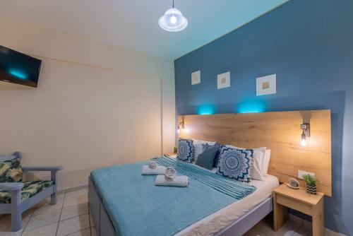 a bedroom with a bed with a blue headboard and a chair at Sarita's Apartments & Suite in Laganas