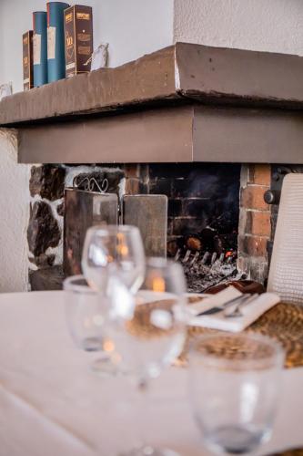 a table with wine glasses in front of a fireplace at Auberge Sainte Marguerite in La Garde