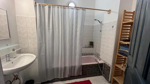 a bathroom with a shower curtain and a sink and a tub at NAPartman Pécs in Pécs