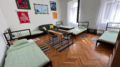 a room with four beds and a table in it at NAPartman Pécs in Pécs