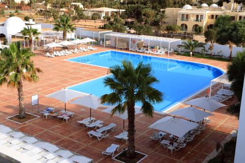 uma vista superior para uma piscina com cadeiras e guarda-sóis em Hotel Riad Meninx Djerba em Djerba