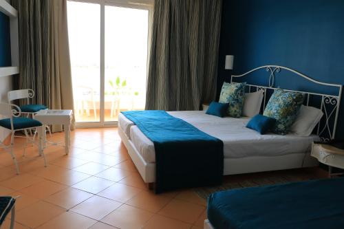 a bedroom with a large bed with a blue wall at Hotel Riad Meninx Djerba in Djerba