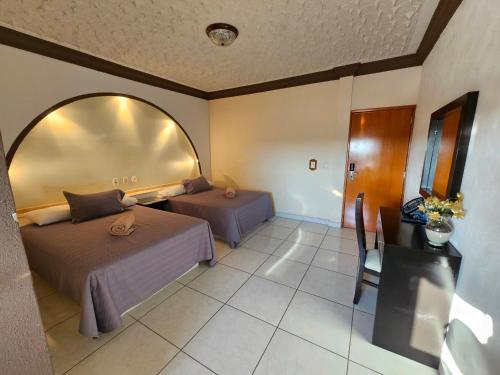 a room with two beds and a table and a mirror at Hotel lito in Nuevo Vallarta 