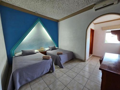 a bedroom with two beds and a blue wall at Hotel lito in Nuevo Vallarta 
