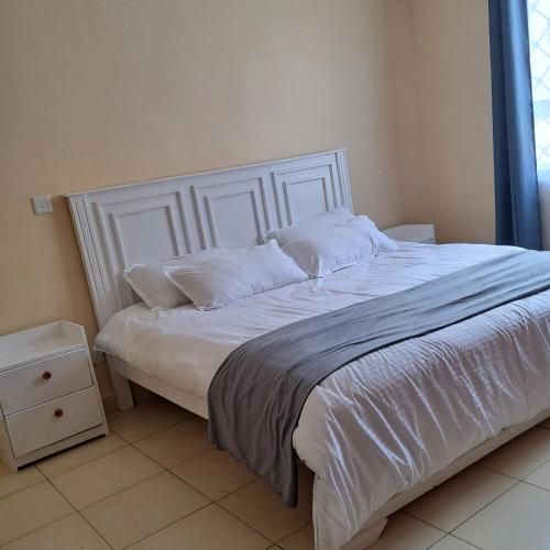 - un lit avec des draps et des oreillers blancs dans une chambre dans l'établissement Shiks Apartment retreat, à Nairobi