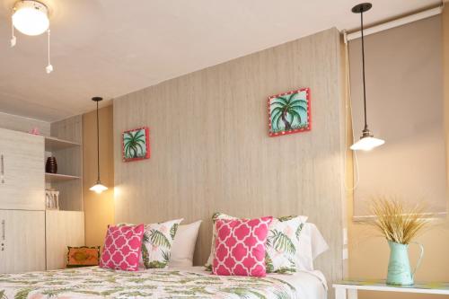 a bedroom with a bed with pink and green pillows at Casa Congo & Casa Rayo Verde - Restaurante - Galeria de arte in Portobelo