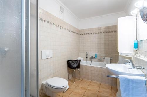 a bathroom with a toilet and a sink and a tub at Ferienwohnung Juliane in der Villa zum Kronprinzen direkt gegenüber der Saarow Therme in Bad Saarow