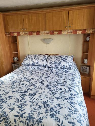 a bedroom with a bed with a blue and white bedspread at Beautiful Caravan in Ingoldmells