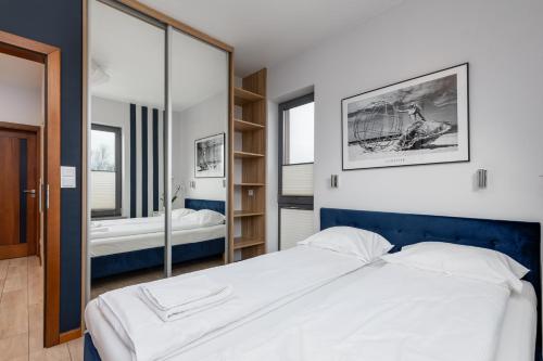 a bedroom with a large white bed and a mirror at Exclusive Zefir Sauna & Grill in Międzywodzie