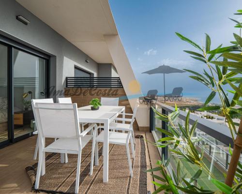 una mesa blanca y sillas en un balcón con vistas al océano en CASCADA del MAR I - GRAN ALACANT en Gran Alacant
