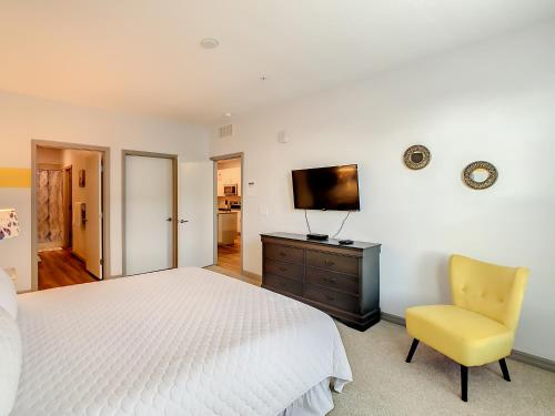 a bedroom with a white bed and a yellow chair at Spacious Apartment Near Disney in Kissimmee