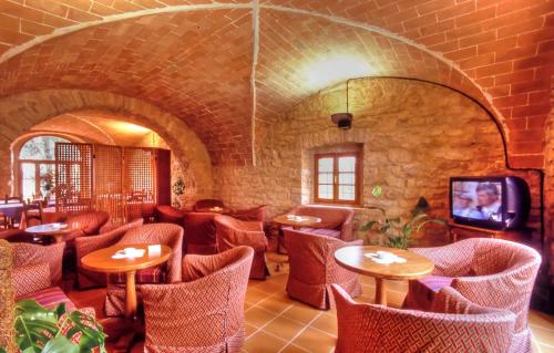 a restaurant with tables and chairs and a tv at Hotel Residence Villa Rioddi in Volterra