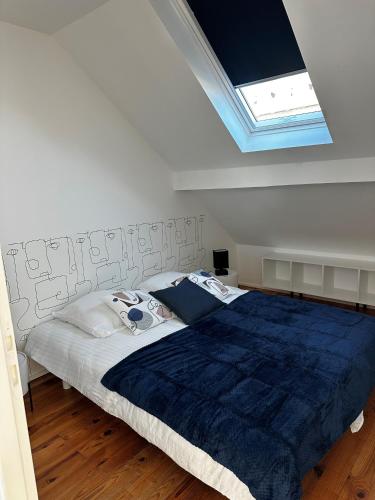 a bedroom with a large bed with a blue blanket at L'atelier du peintre in Dunkerque