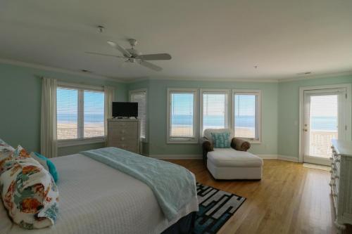 a bedroom with a bed and a chair and windows at Claire's Rendezvous in Tybee Island