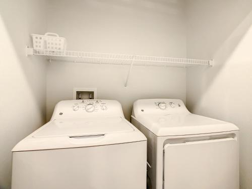 a laundry room with two white washers and a shelf at Spacious Apartment Near Disney in Kissimmee