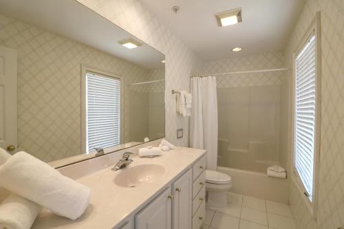 y baño con lavabo, aseo y espejo. en Claire's Rendezvous, en Tybee Island