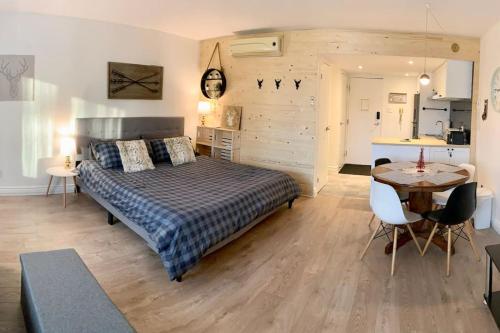 a bedroom with a bed and a table and a kitchen at Loft LaprèSKI, Lit king, sauna/piscine et montagne in Saint-Férréol-les-Neiges