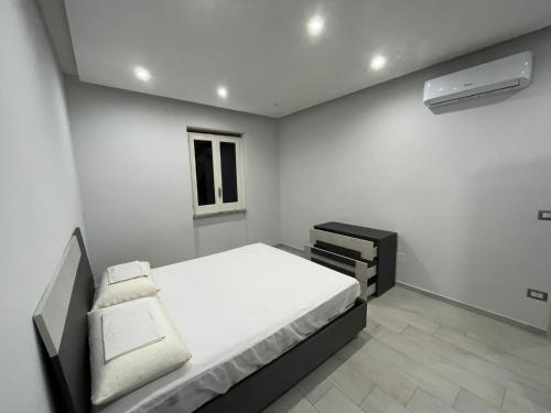 a white bedroom with a bed and a window at Agavi's Home 1 in Baia Domizia