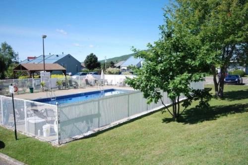 a fence around a swimming pool with a tree at Loft LaprèSKI, Lit king, sauna/piscine et montagne in Saint-Férréol-les-Neiges