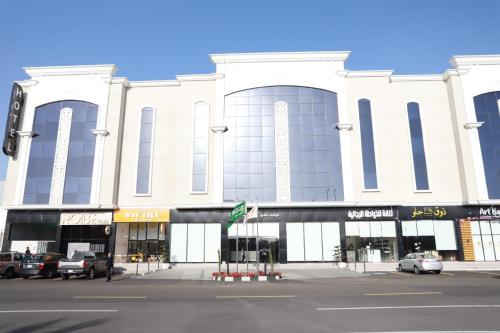فندق توليب فيو في خميس مشيط: مبنى ابيض كبير فيه سيارات تقف امامه