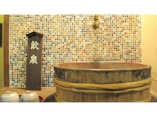 a wooden tub in a bathroom with a tiled wall at Yoro Onsen Honkan - Vacation STAY 09622v in Onomichi