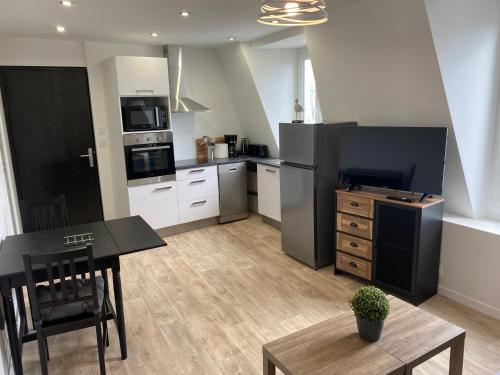 Il comprend une cuisine équipée d'un réfrigérateur noir et d'une table. dans l'établissement Centre ville Granville à 50m de la mer - ANCV accepté, à Granville