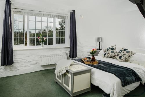 a white bedroom with a bed and a window at Shilla Mill - Just off the Beach in Polzeath
