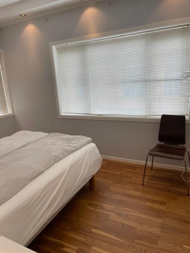 ein Schlafzimmer mit einem Bett, einem Stuhl und einem Fenster in der Unterkunft Eiganesveien 1 in Stavanger