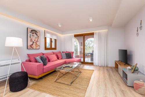 sala de estar con sofá rosa y TV en Lola's Luxury Apartments, en Liapades
