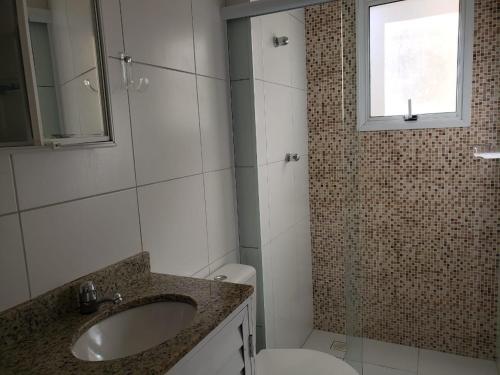 a bathroom with a sink and a toilet and a window at Thel Ubatuba - Apto 27/A, Monte Carlo - Praia Grande in Ubatuba