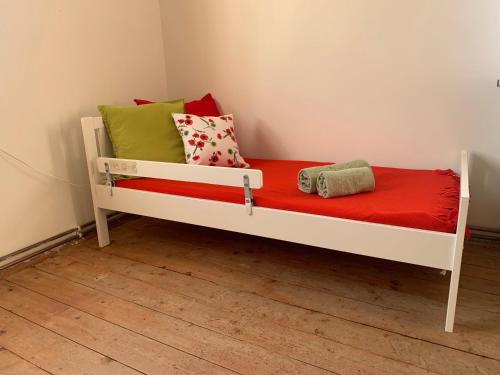 Una cama blanca con almohadas rojas y verdes. en Dvorek na správném místě - Salajna 17 en Dolní Žandov