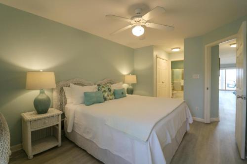 um quarto com uma cama branca e uma ventoinha de tecto em Atlantic Sunrise em Tybee Island