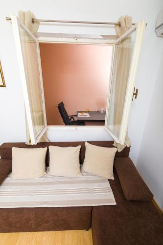 a couch with pillows in a room with a window at Guest House Marinna in Vrboska