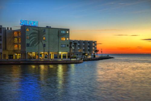 a building on the water with a sunset in the background at Sailport Waterfront Suites in Tampa