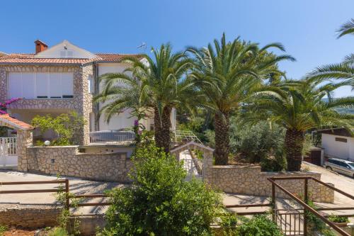 a house with palm trees in front of it at Guest House Marinna in Vrboska