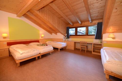 a bedroom with two beds and a desk in a room at Hotel Casa Alpina - Alpin Haus in Selva di Val Gardena