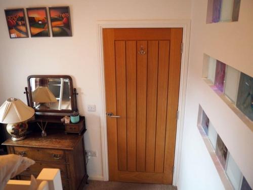 a room with a wooden door and a desk with a mirror at Fern Lodge Angus, Kirriemuir in Angus