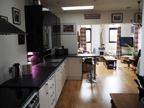 a kitchen with black counter tops and a living room at Fern Lodge Angus, Kirriemuir in Angus