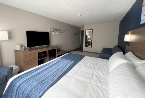 a hotel room with a large bed and a flat screen tv at Hilltop Inn & Suites in Grove