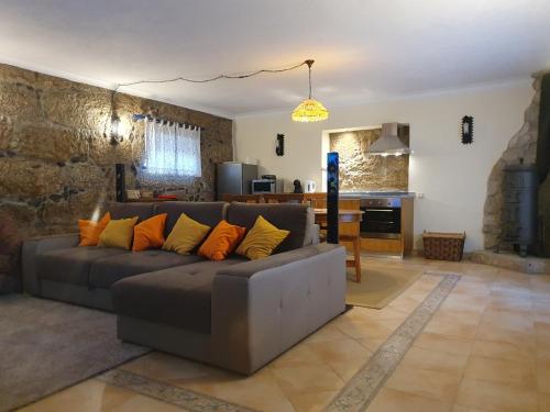a living room with a gray couch with orange pillows at Casa dos Chãos in Cabeceiras de Basto