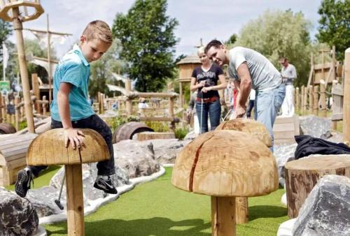 a young boy jumping over wooden mushrooms in a playground at Cottage 213 in Sunparks Oostduinkerke with free parking and garden in Koksijde