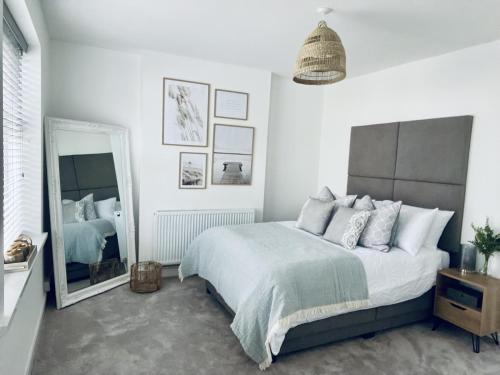 a bedroom with a large bed and a mirror at Modernised Cottage in the Heart of Sketty in Swansea