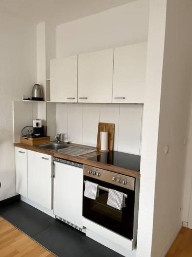 a small kitchen with white cabinets and an oven at Zentral, gemütlich, Messe nah! BE1L in Essen