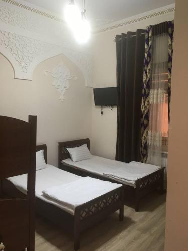 2 camas individuales en una habitación con ventana en Uzbek House, en Samarkand