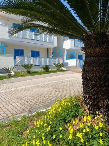 a palm tree and flowers in front of a building at Residenza Le Spiagge in Sperlonga