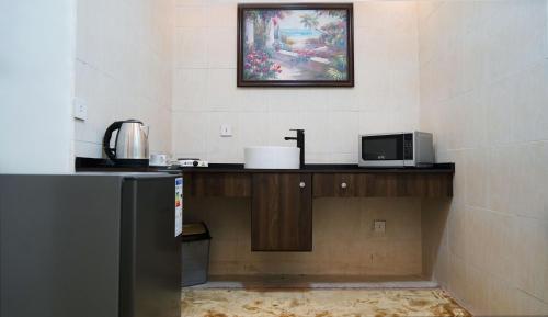 eine Küche mit einer Theke mit einer Mikrowelle und einem Bild an der Wand in der Unterkunft Sorate Hotel Apartment in Amman