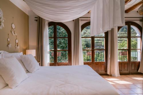 1 dormitorio con cama blanca y ventanas grandes en Valley Club Ibiza - Boutique Agroturismo, en Sant Joan de Labritja