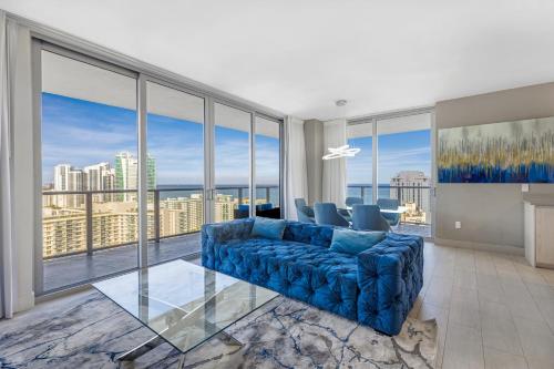 a living room with a blue couch and large windows at HYDE BEACH HOUSE RESORT #2101 - MILLION APARTMENT 2BD/2BA. DIRECT OCEAN VIEW. 1 MIN FROM BEACH. 6 GUESTS. in Hollywood