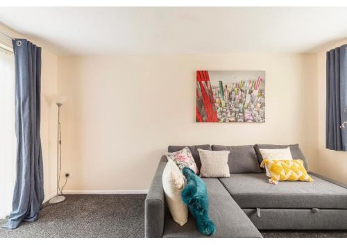 ein Wohnzimmer mit einem grauen Sofa und einem Gemälde in der Unterkunft New Manchester Getaway Home - Free Parking in Manchester