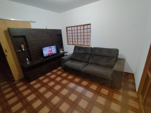 een woonkamer met een bank en een flatscreen-tv bij POUSADA ROSA BRANCA in Uberlândia